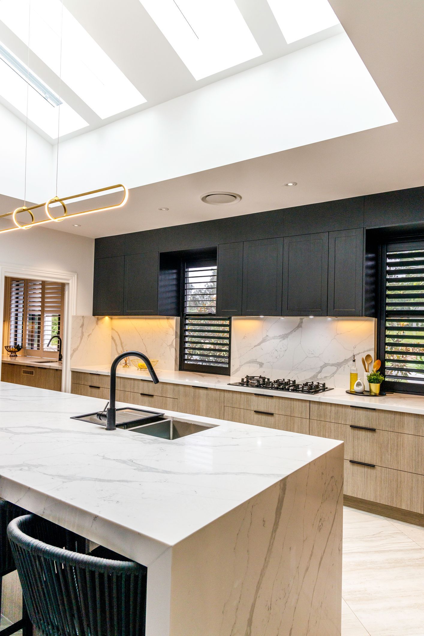 Skylight in modern kitchen, stone bench tops, stylish two-tone cabinetry.
