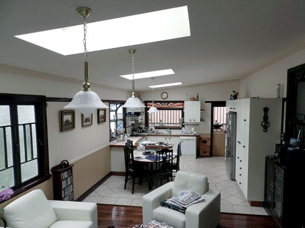 Interior view of a kitchen and living area, with skylights, white walls, and a dining table.