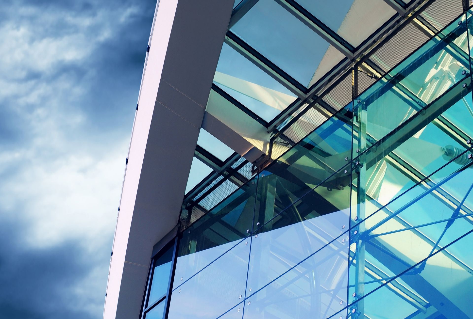 Modernes Gebäude mit Glasfassade, die den blauen Himmel reflektiert.