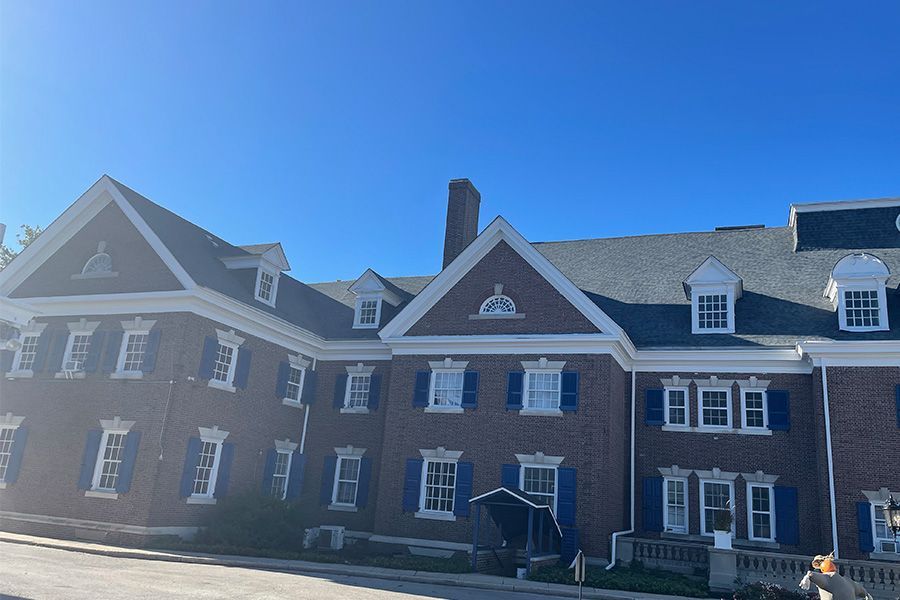 A large brick building with blue shutters and a blue sky in the background