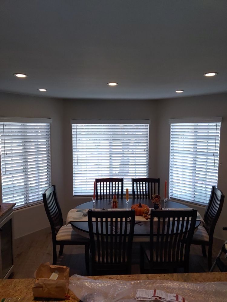A dining room with a table and chairs and blinds on the windows.