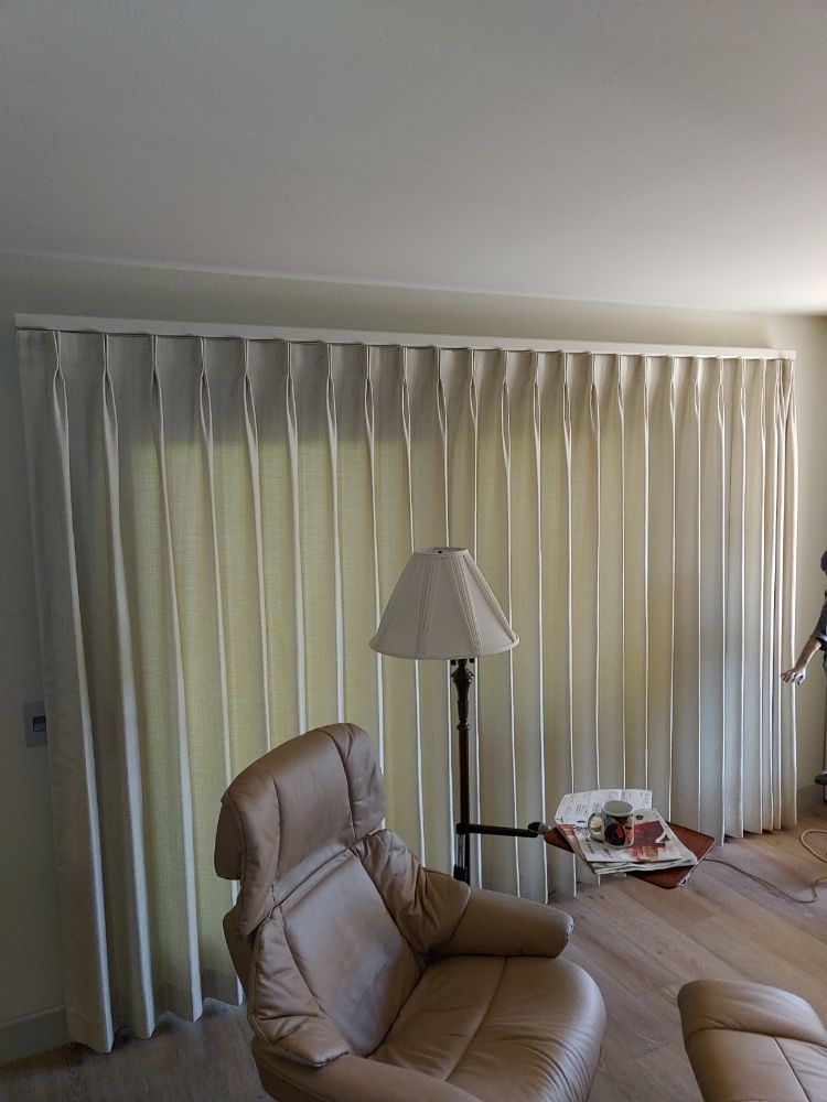 A living room with a chair , lamp , table and curtains.