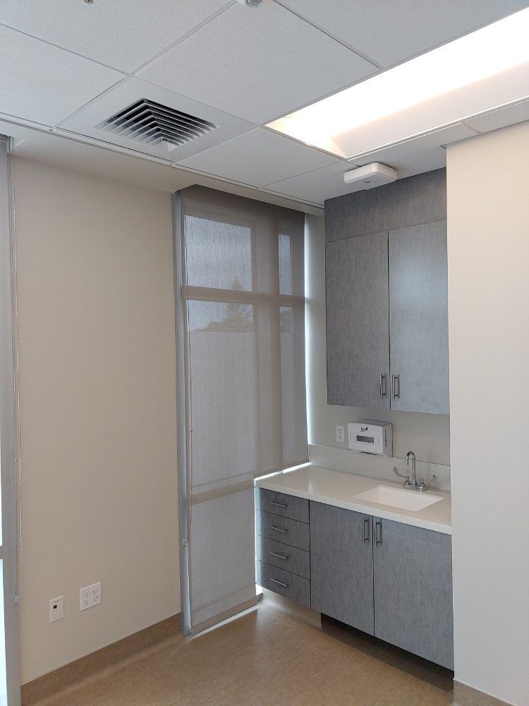 An empty room with a sink , cabinets , and a window.