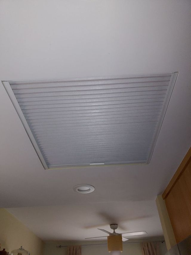 A room with a ceiling fan and a window with blinds on it.