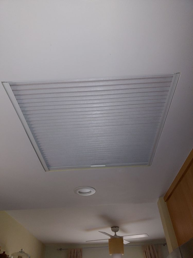 A room with a ceiling fan and a window with blinds on it.