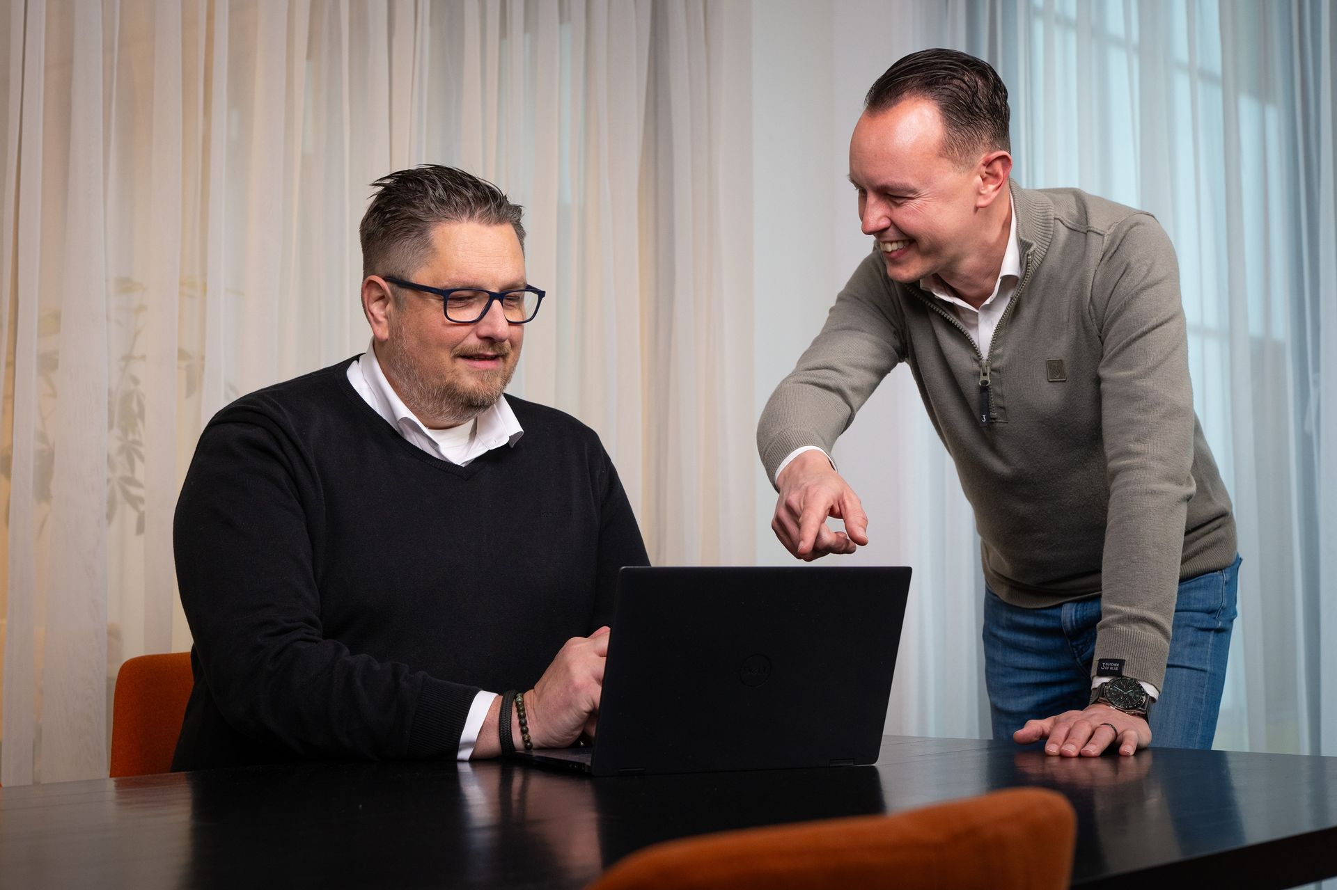 A man and a woman are sitting at a table with a laptop and a tablet.