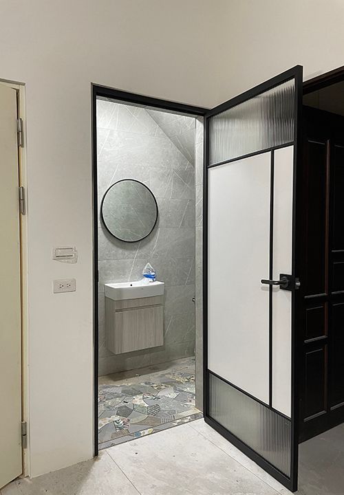 A bathroom with a sink and a mirror behind a glass door.