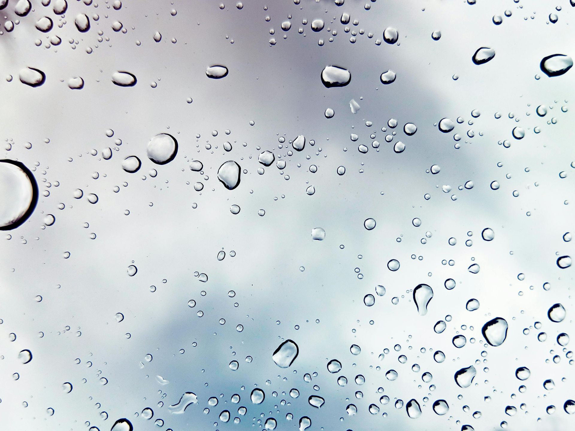 Water drops on a window with a blue sky in the background