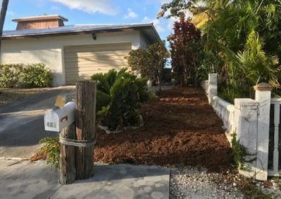 A mailbox is tied to a wooden post in front of a house.