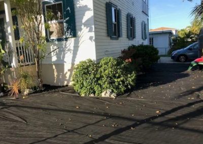 A white house with blue shutters and a car parked in front of it.