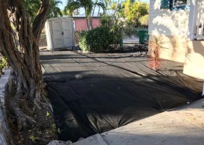 A black tarp is covering a driveway in front of a house.