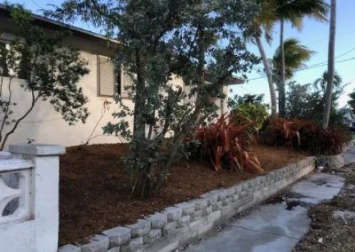 A white house with a brick wall in front of it