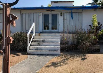 A white house with stairs leading up to the front door.