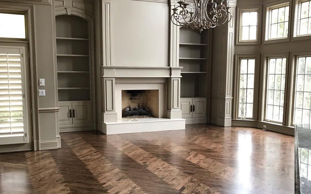 There is a fireplace in the middle of the room with a hardwood floor