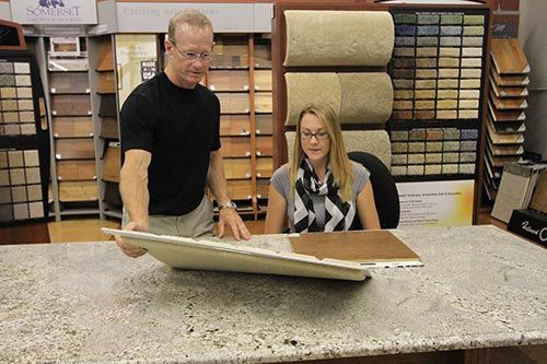 A man and a woman are looking at a piece of carpet in a store