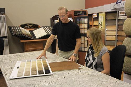A man and a woman are looking at different types of flooring in a store