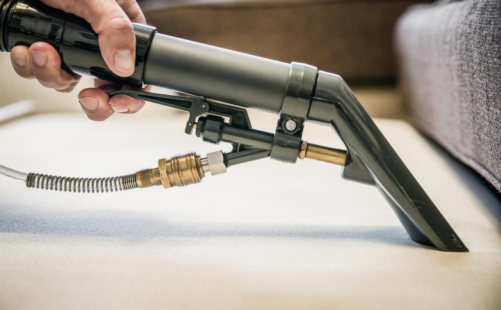 Person is Using a Vacuum Cleaner to Clean a Couch — Boyne Carpet Cleaning in Iveragh, QLD