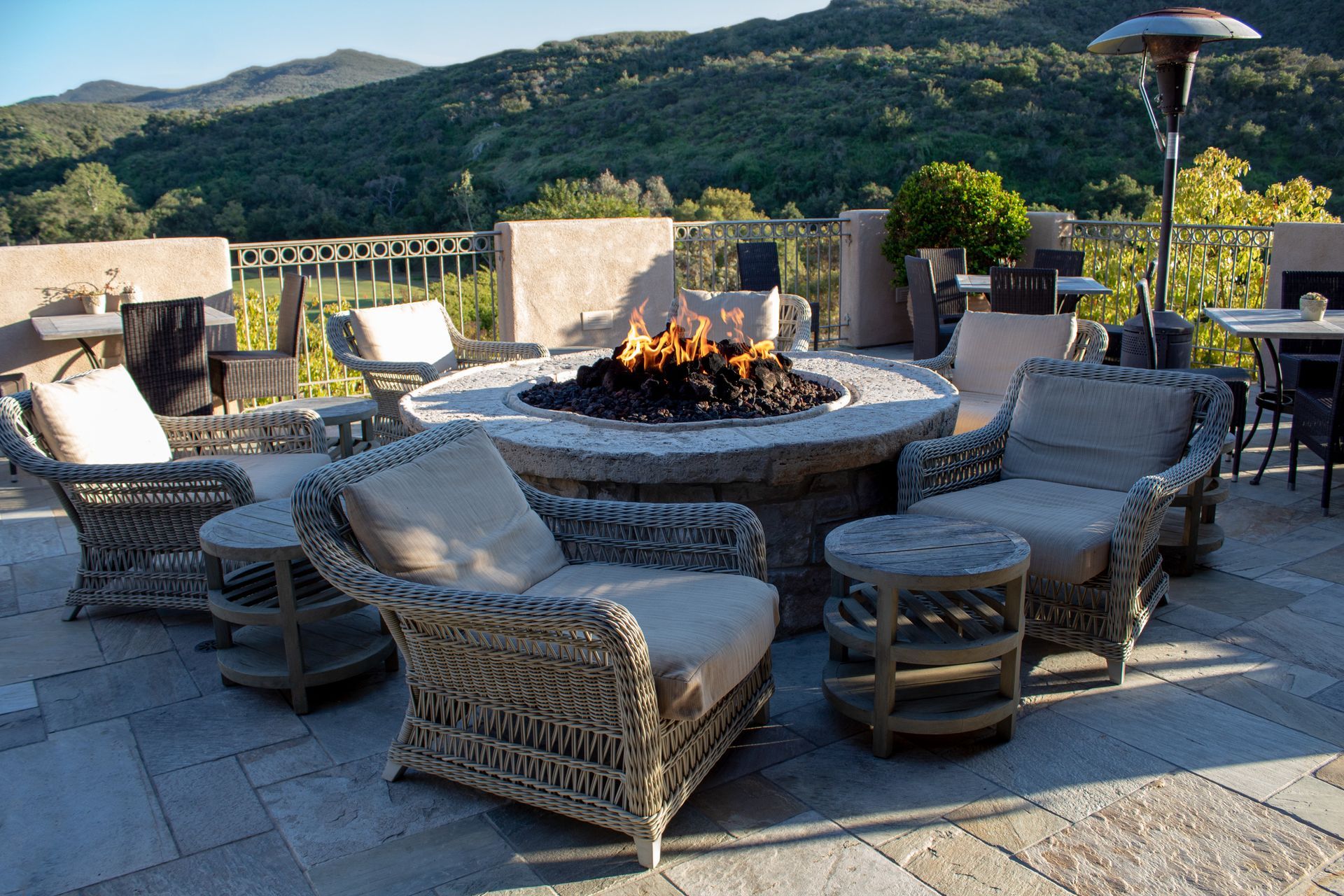 Outdoor seating area with fire pit, wicker chairs, and mountain view.