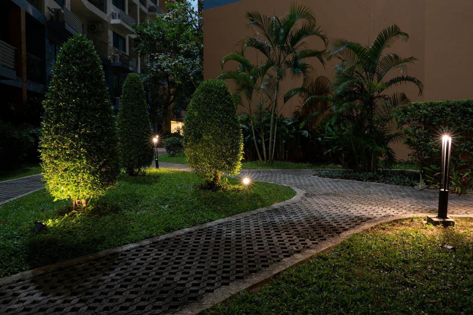 Lit garden path with trees, lawn, and pathway lighting at dusk.