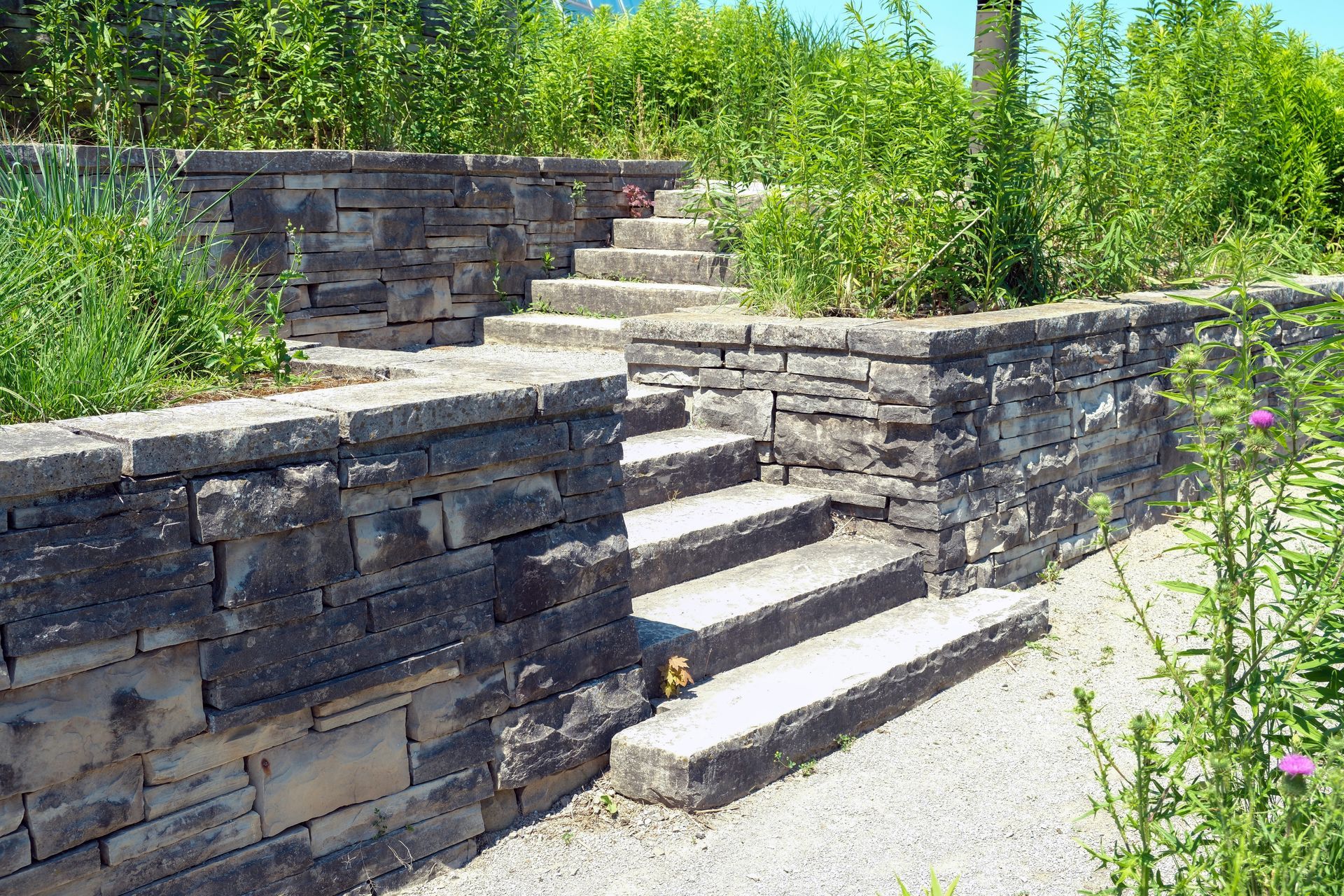 Stone steps ascending between stacked stone walls, surrounded by greenery.