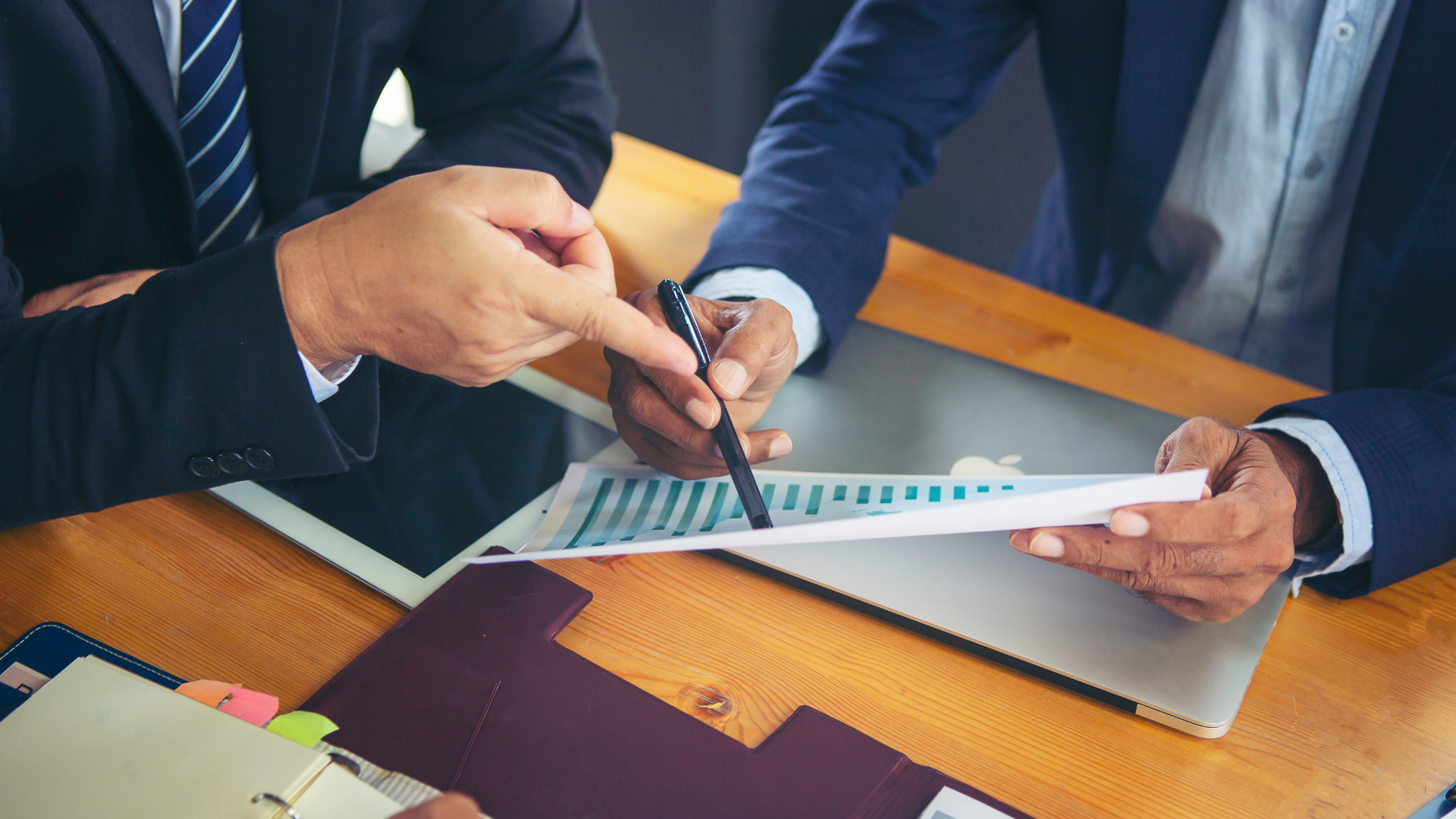 Businesspeople reviewing charts and pointing at a financial document on a conference table