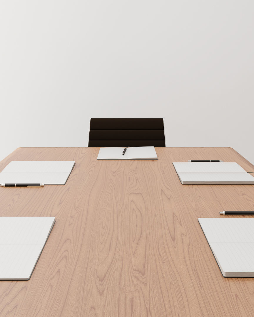 Empty conference room with a wooden table, brown chairs, and white notepads at each seat