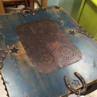 Rustic blue wooden table top featuring a central patterned tin inlay, accented with metal horseshoes and star cutouts.
