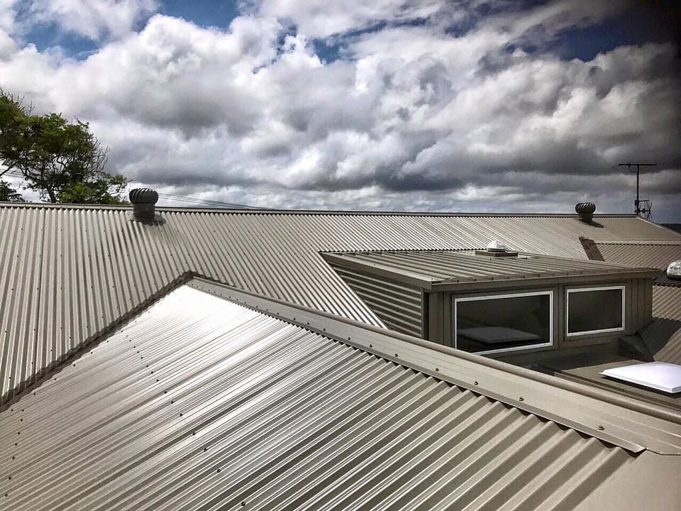 A Close Up Of A Roof With A Cloudy Sky In The Background — Roofing in Newcastle, NSW