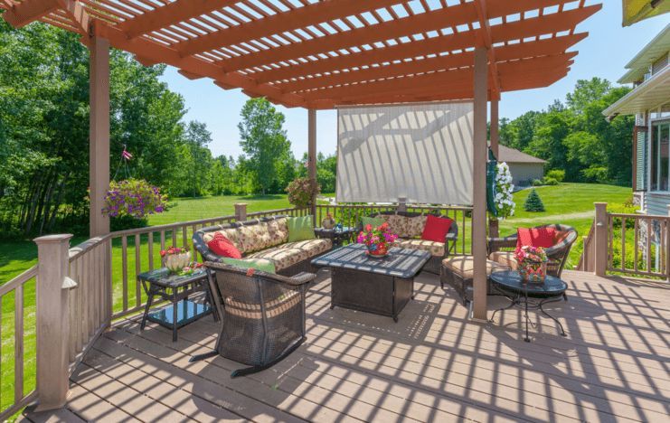 A deck with a pergola and patio furniture underneath it.