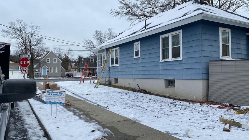 A blue house is sitting on the side of the road in the snow.