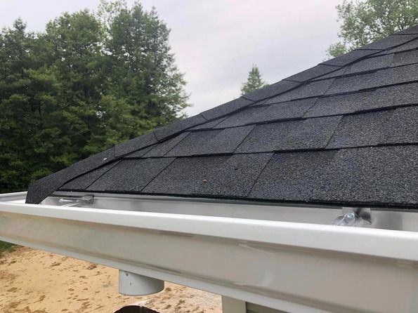 A close up of a black roof with a white gutter.