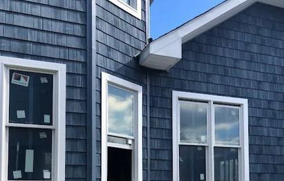 A blue house with white trim and windows is being built.