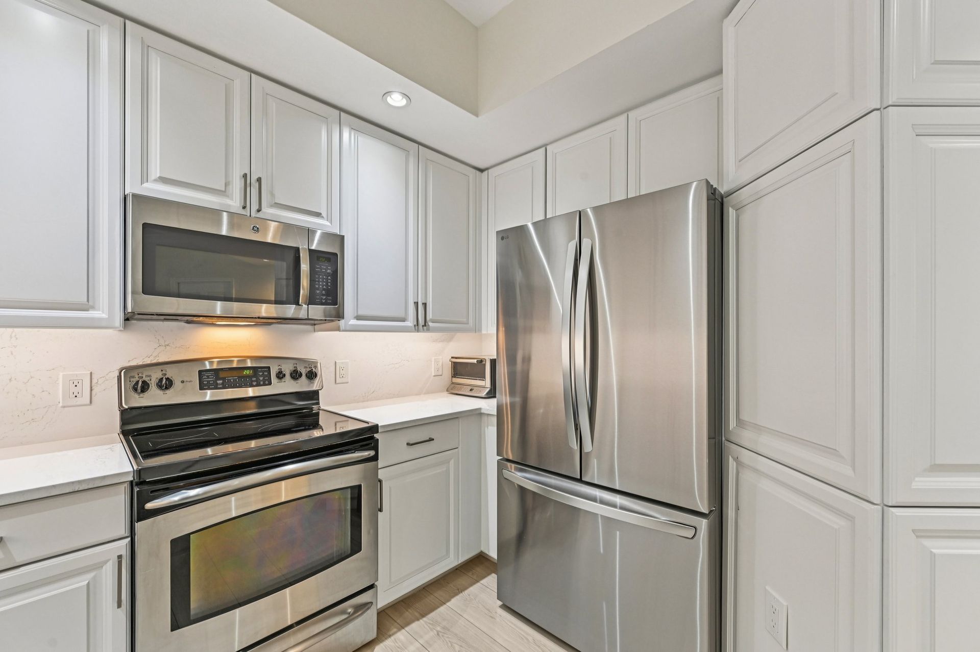 Modern kitchen with stainless steel appliances and white cabinets.