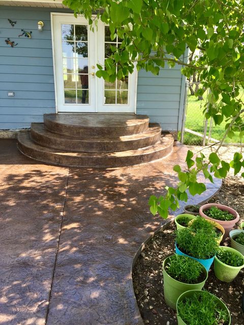 A patio with steps and potted plants in front of a house