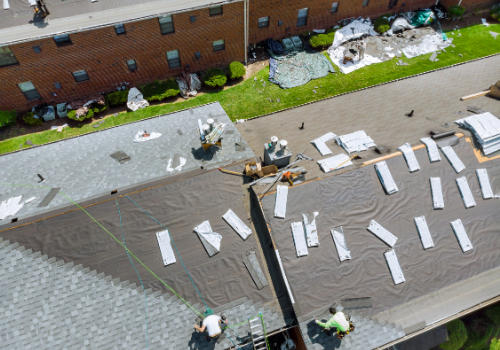 Picture of a crew working on a roof replacement of a large home.