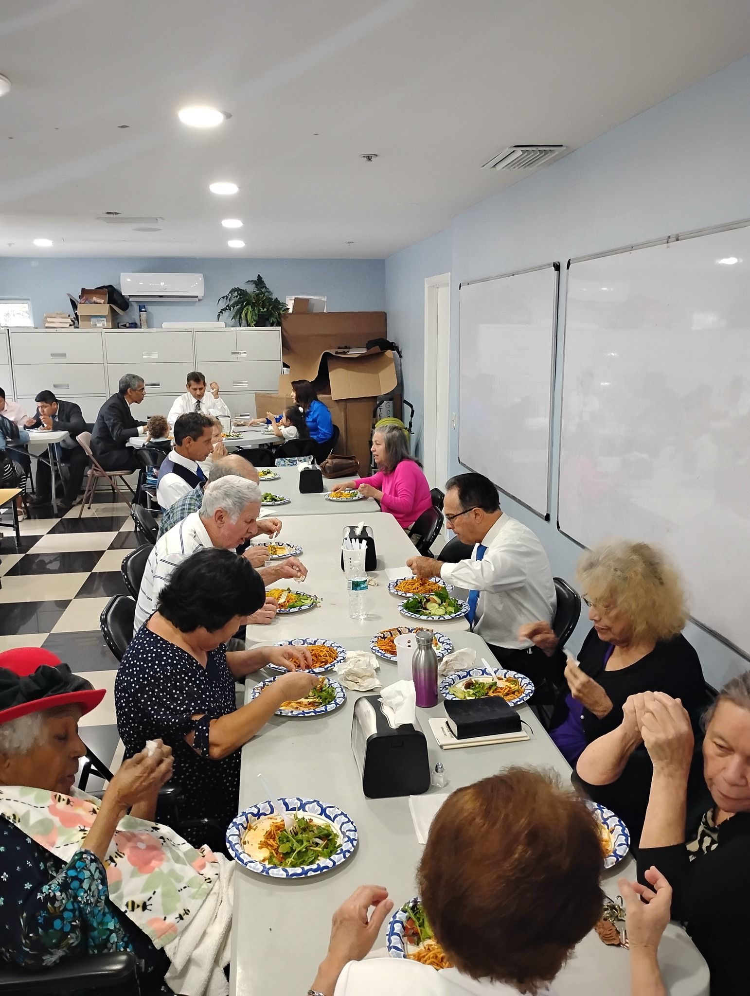 A group of people are sitting at a long table eating food.