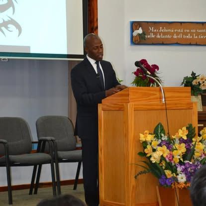 A man in a suit stands at a podium giving a speech