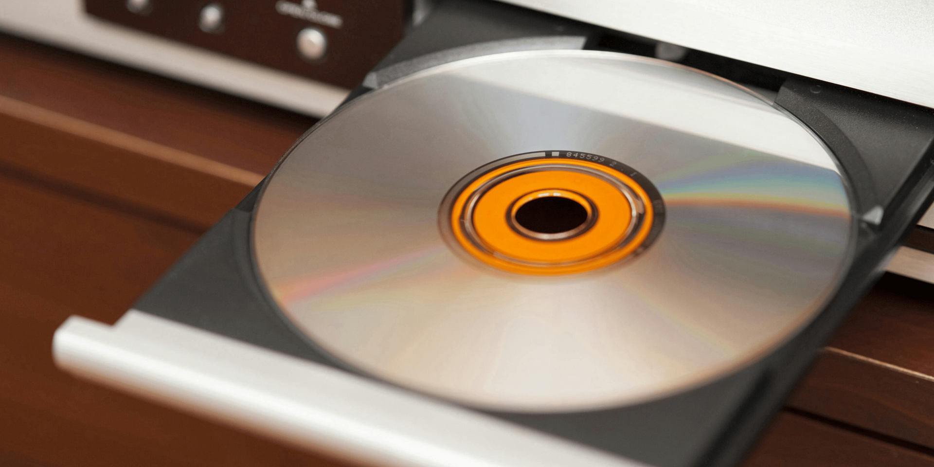 A CD in a player tray. The tray is open, and the CD is centered with an orange hub.