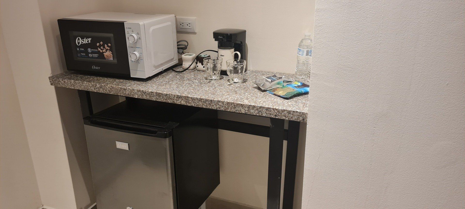 A small kitchenette area with a microwave, coffee maker, mini fridge, and countertop.