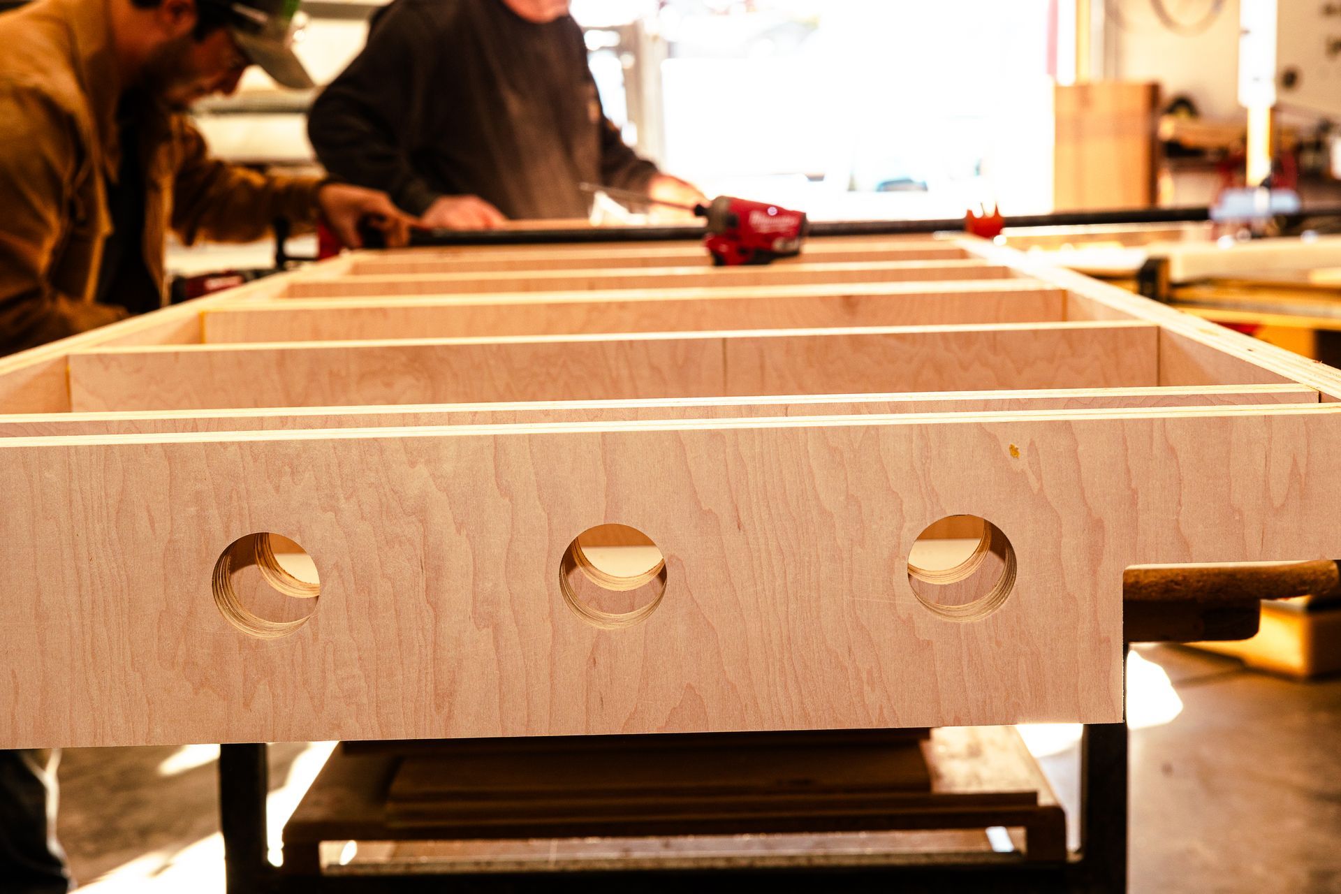 Two men are working on a piece of wood in a workshop