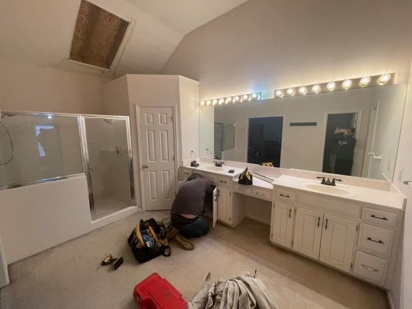 a man is working in a bathroom with a large mirror in Bonner Springs