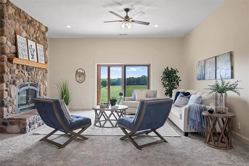 a living room with a fireplace , couch , chairs and a ceiling fan .