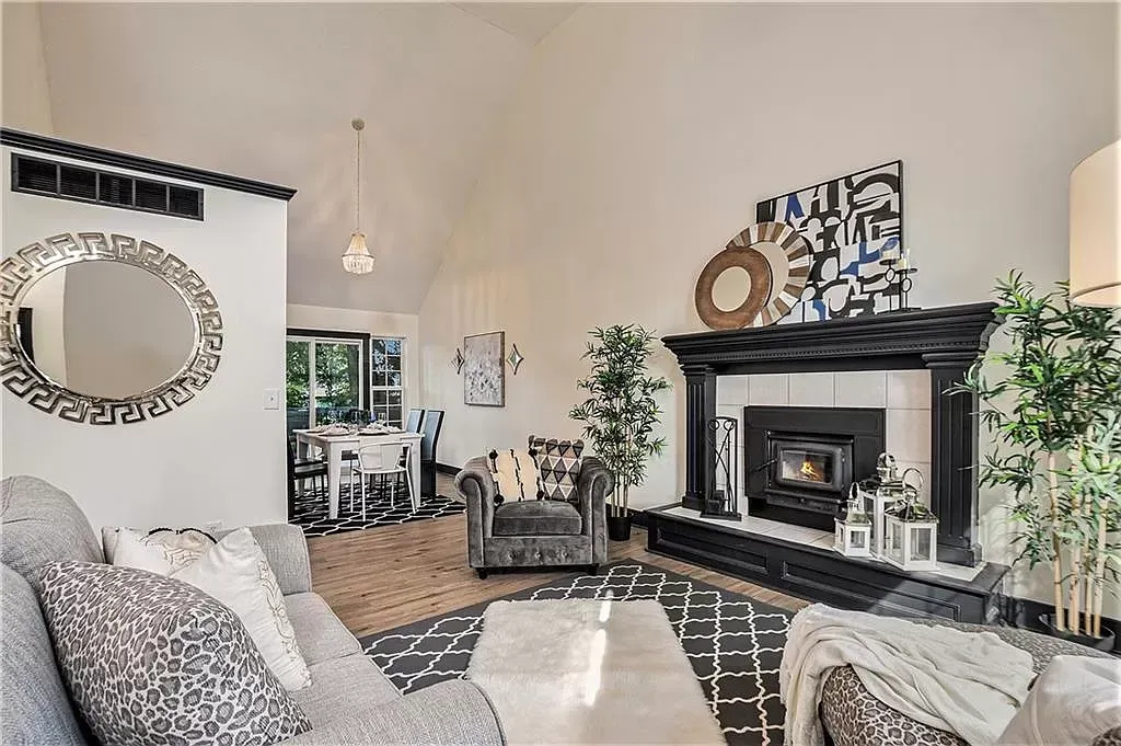 a living room with a couch , chair , fireplace and mirror .