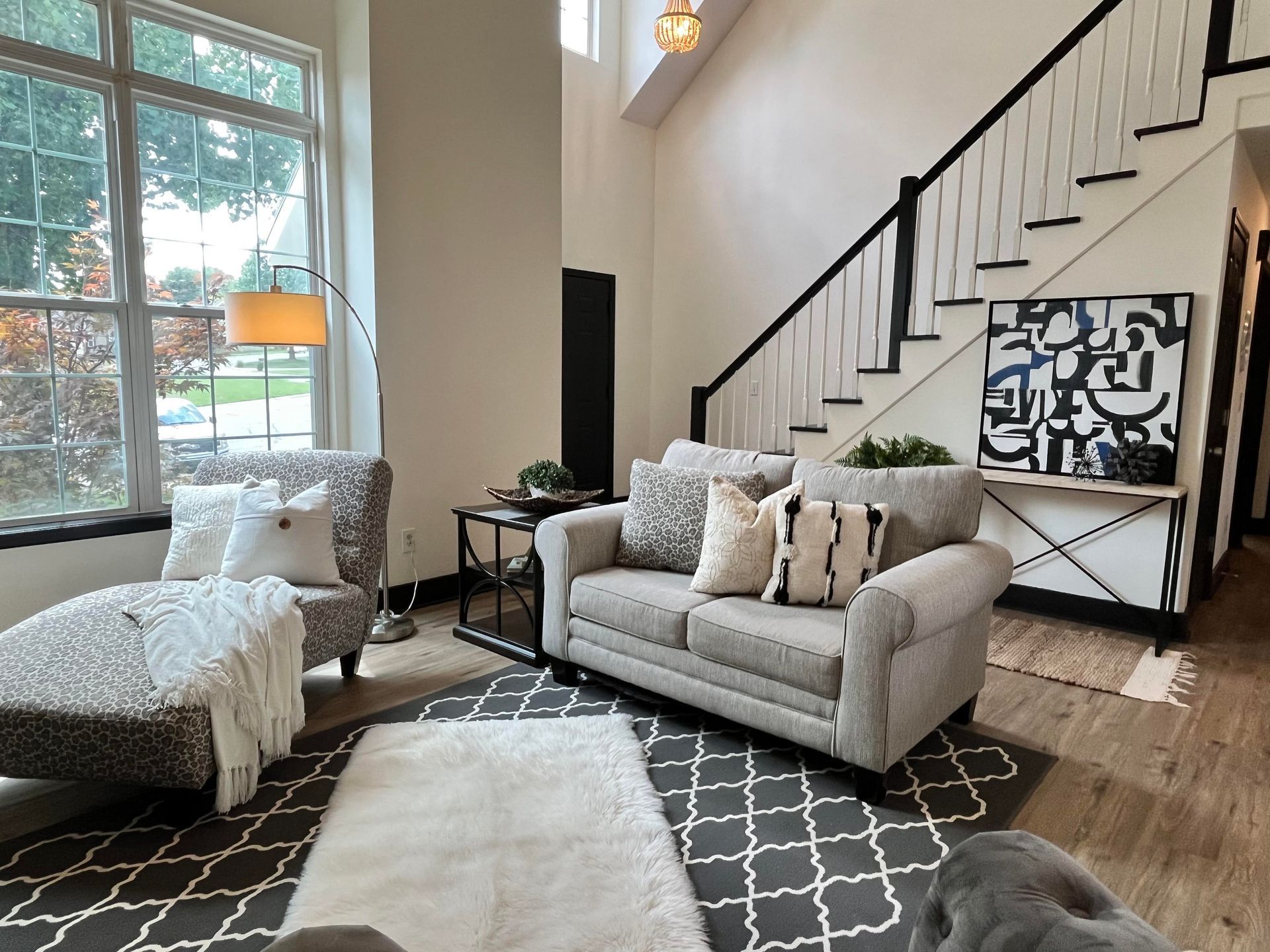 a living room with a couch , chair , rug and stairs .