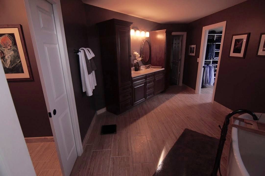 Hands in gloves attaching a cabinet hinge to a white cabinet door.