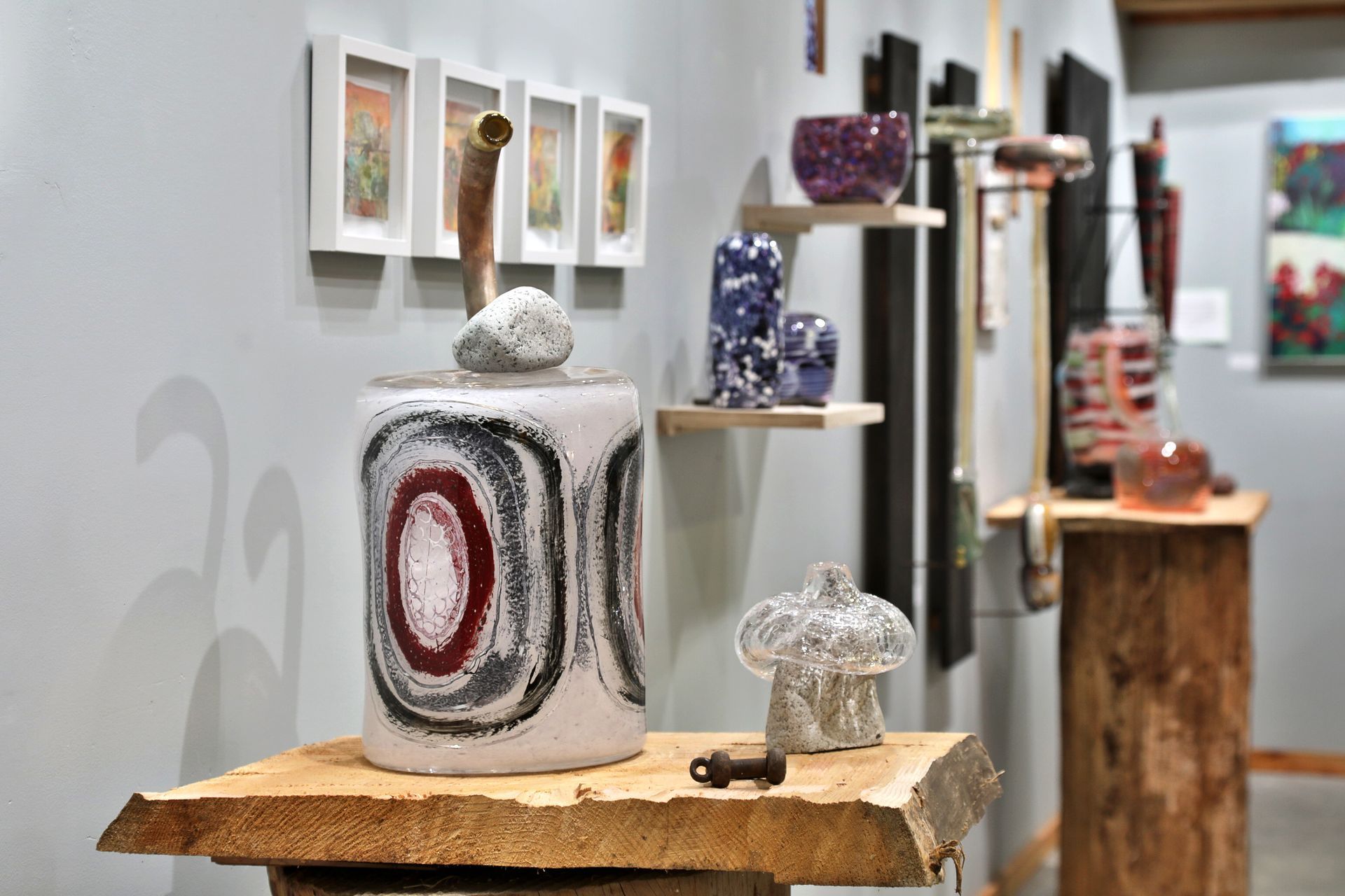 Art gallery with ceramic jar, sculptures, and paintings on display.