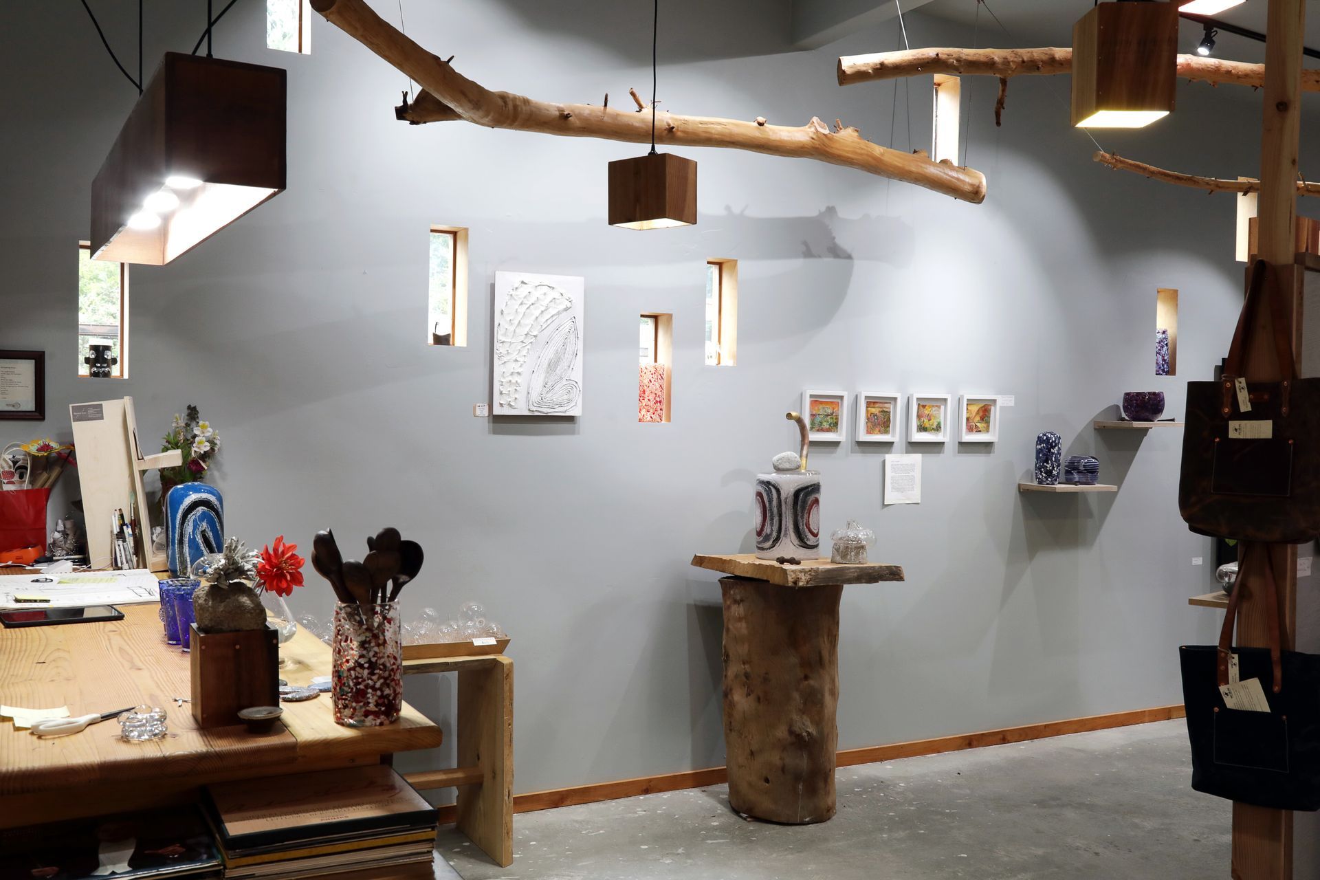 Art gallery with gray walls, wooden fixtures, and displayed artwork.