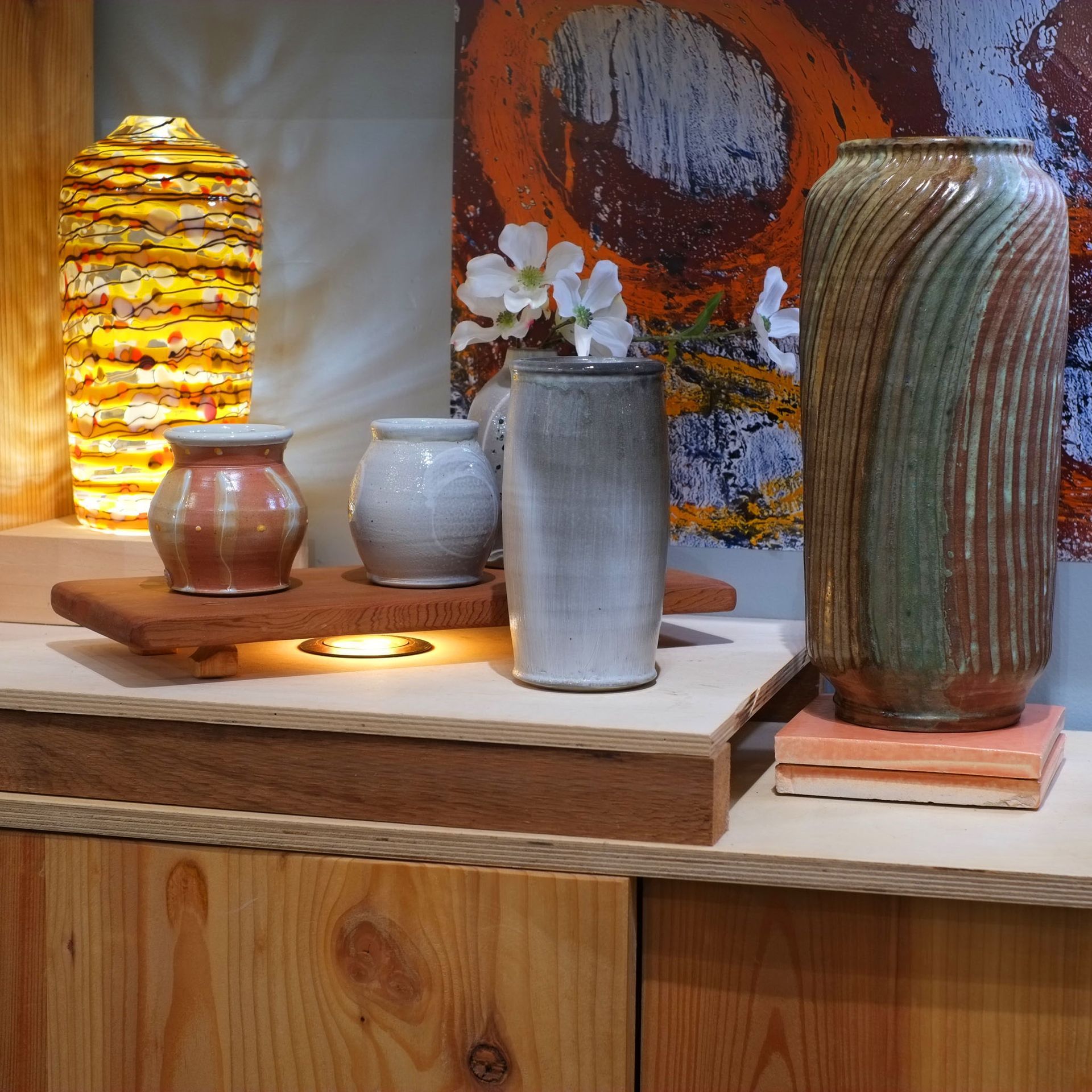 Various ceramic vases displayed on wooden shelves against a colorful backdrop; interior shot.