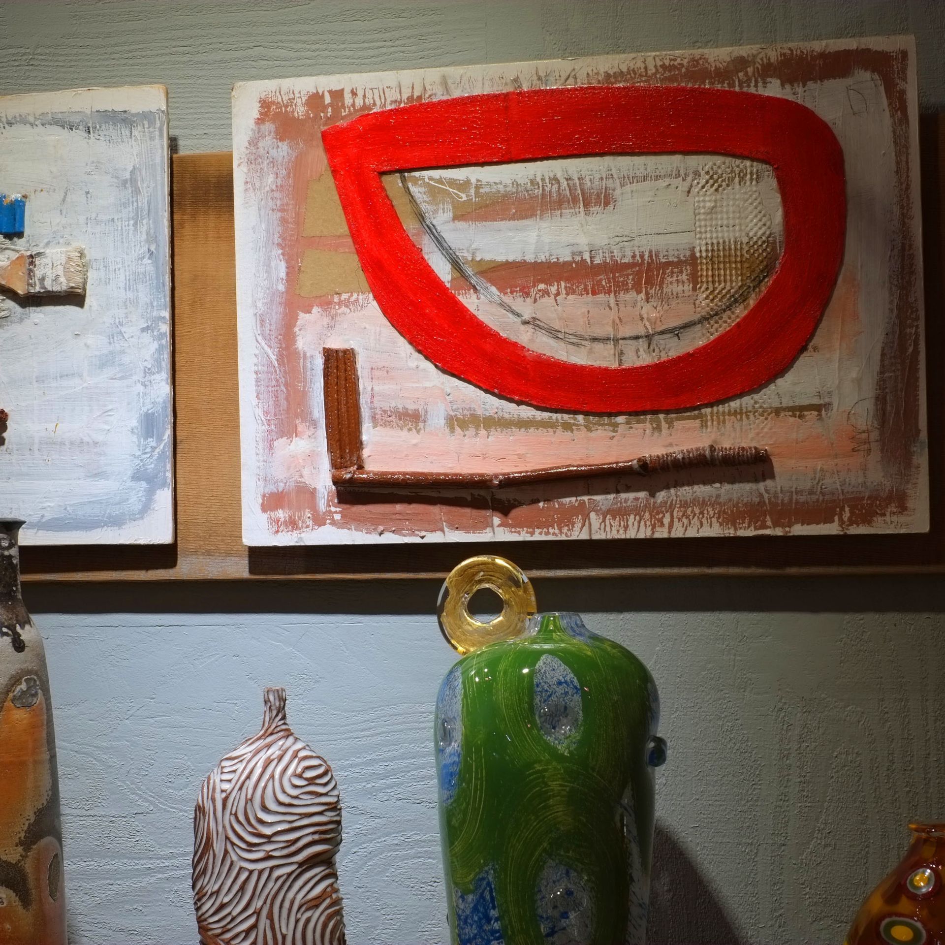 Artwork: Abstract painting with red, white, and brown elements. Ceramic vases below in various colors.