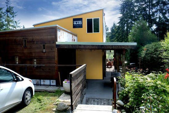 Modern house with mustard yellow and wood siding, covered walkway, and white car parked outside.